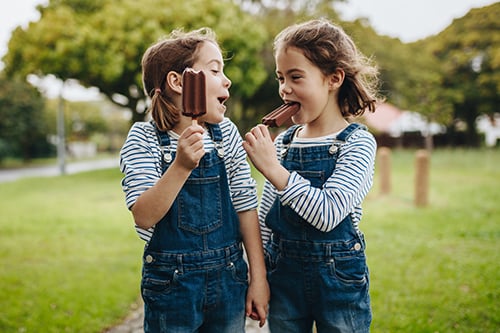  two young girls eating popsicles