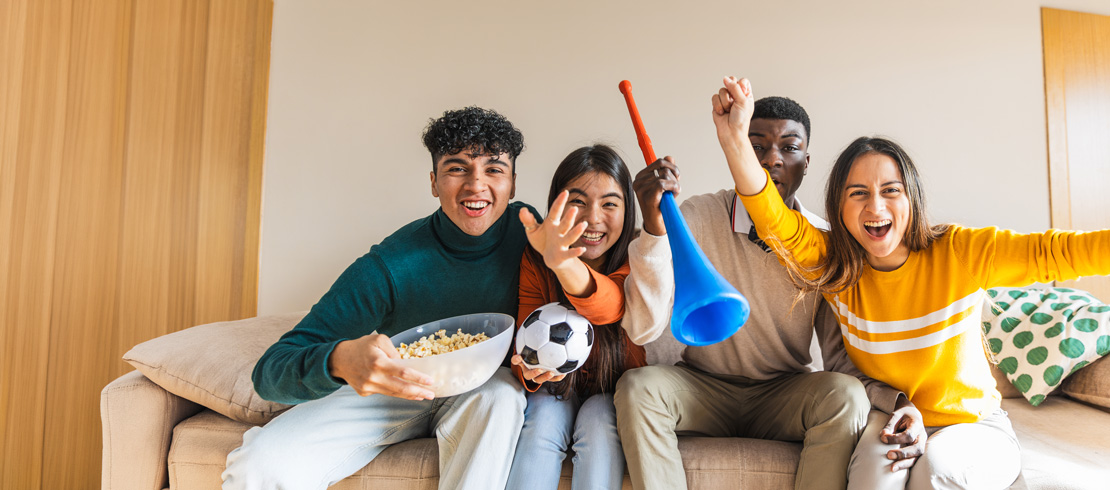 people cheering while watching a soccer match from home