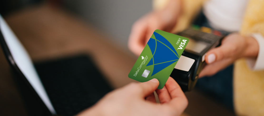 person tapping their Delta Community Credit Union debit card to pay