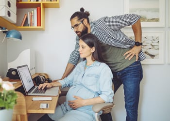 couple expecting a baby looking at a laptop