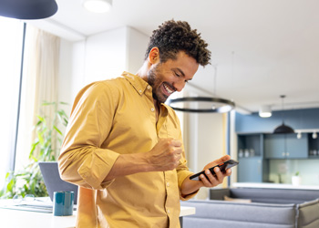 man smiling while looking at his smartphone