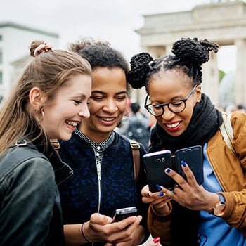 three friends laughing and looking at phone