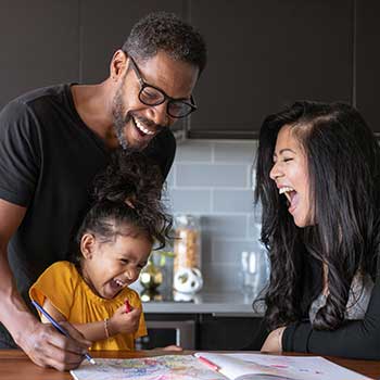 young girl coloring with family