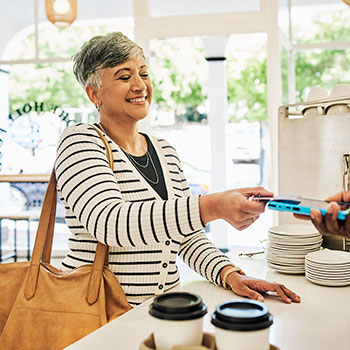 woman at café smiling and paying with credit card