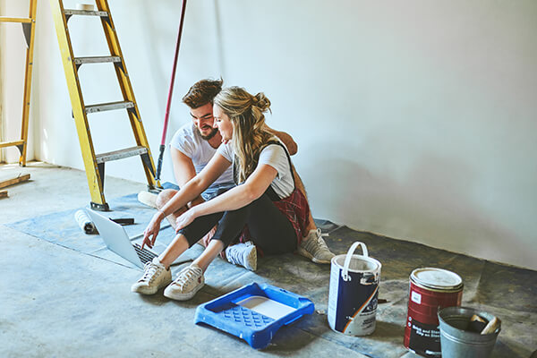 a young couple using a laptop while busy with renovations at home