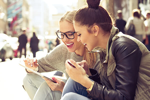 young women using tablet and sharing information about delta community refer-a-friend