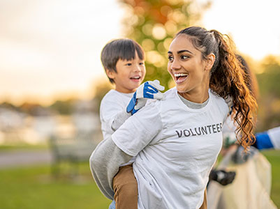 a smiling volunteer gives a child a piggyback ride
