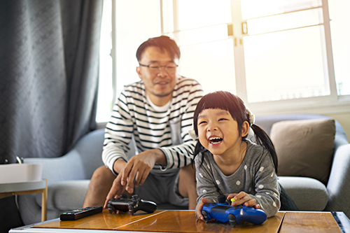 dad and young daughter playing video games